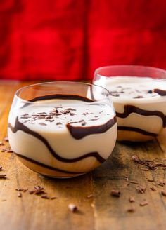 two desserts sitting on top of a wooden table next to each other in glasses