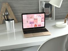 an open laptop computer sitting on top of a white desk next to a lamp and pictures