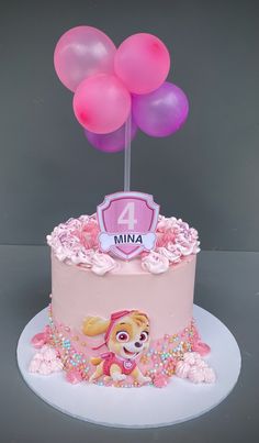 a birthday cake with pink frosting and lots of balloons in the shape of a dog