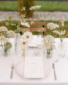 the table is set with white flowers and silverware