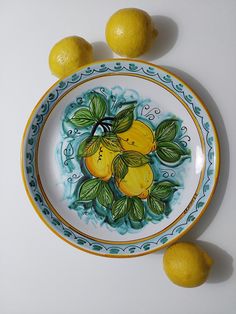 two lemons are sitting on a plate next to three lemons that have been painted onto them