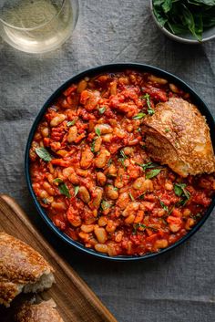 a bowl filled with beans and meat next to bread