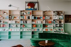 a living room filled with green couches and bookshelves next to a coffee table