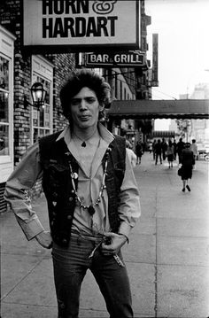 a man is standing on the sidewalk with his hands in his pockets