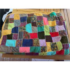 a multicolored patchwork blanket sitting on top of a wooden bench