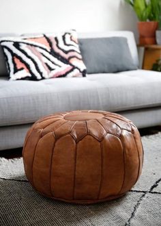 a brown leather ottoman sitting on top of a rug in front of a white couch