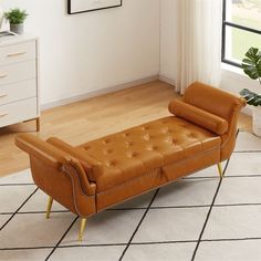 a brown leather chaise lounger sitting on top of a tiled floor next to a window