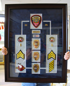 a person holding up a framed display with badges on it's sides and in front of them