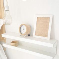 a white shelf with a clock and lamp on it