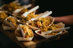 there are many small bowls with food in them on the wooden tray and one is filled with rice