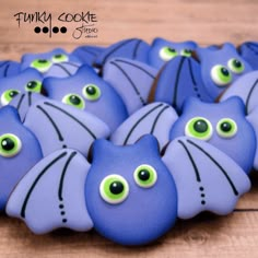 blue decorated cookies with green eyes and black cat's eyes on them, sitting on a wooden surface