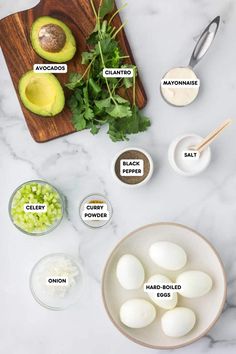 ingredients to make an avocado salad laid out on a marble counter top with text overlay