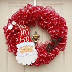 a christmas wreath with a santa clause on it and a bell hanging from the front door