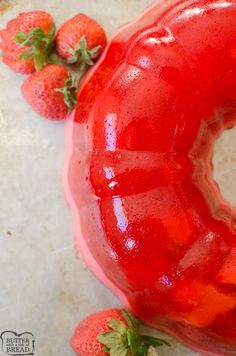 a red donut sitting on top of a counter next to strawberries