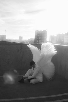 a man sitting on the ground next to an angel like object in front of him