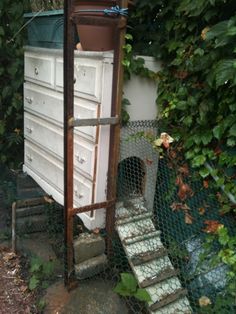 an old dresser sitting on the side of a fenced in area with stairs leading up to it