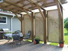 a patio covered in wooden pergols with chairs and table next to potted plants