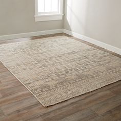 an area rug in the corner of a room with wood flooring and white walls