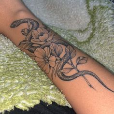 a woman's arm with a snake and flowers tattoo on it