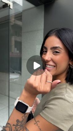 a woman with tattoos on her arm and wrist smiling at the camera while holding an apple watch