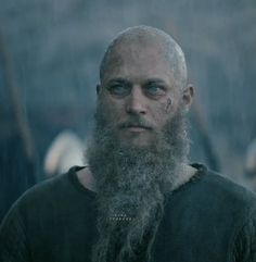 a man with long grey hair and beard standing in the rain