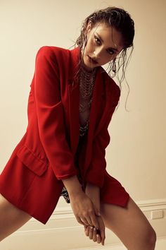 a woman in a red blazer and shorts posing for the camera with her hands on her hips