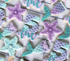 some decorated cookies are sitting on a wooden table with the words live in blue and purple