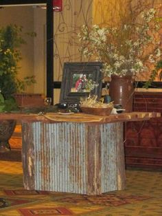 a table that has some flowers in it and a picture frame on the table top