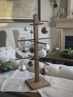 a christmas tree with ornaments hanging from it's branches in front of a fireplace