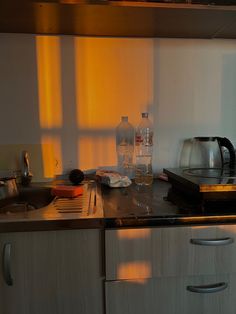 the kitchen counter is cluttered with dishes and bottles, including an electric tea kettle