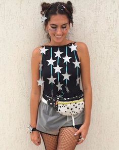 a woman wearing fishnet stockings and tights with stars on her top is posing in front of a white wall