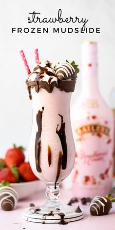 an ice cream sundae with chocolate and strawberries on the table next to it