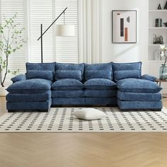 a living room with a large blue couch and white rugs on the wooden floor