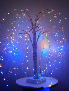 a small tree with multicolored lights on it's branches is shown in front of a blue background