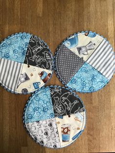 three pieces of fabric sitting on top of a wooden table covered in blue and white