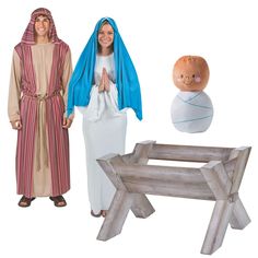 two people dressed in biblical clothing standing next to a wooden bench and stuffed animal doll