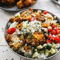 two bowls filled with rice, vegetables and meat on top of a white tablecloth