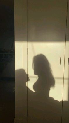 the shadow of a woman standing in front of a closet