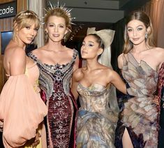 three models pose with one another in front of the camera while wearing dresses and headpieces