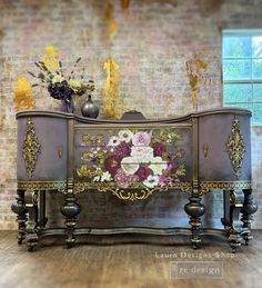 an ornate dresser with flowers on it in front of a brick wall