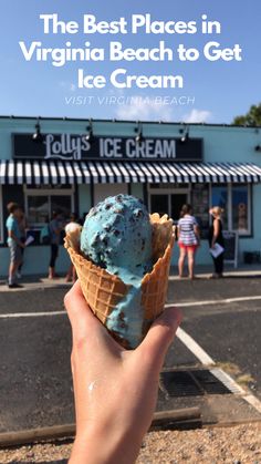 a hand holding an ice cream cone in front of a store