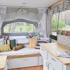 the inside of a camper with lots of pillows