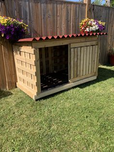 a wooden dog house with flowers on the roof