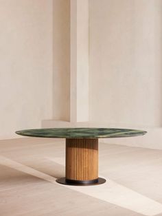 a round table sitting on top of a hard wood floor next to a white wall