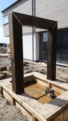 a wooden frame sitting on top of a pile of dirt in front of a building