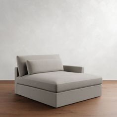 a gray couch sitting on top of a wooden floor next to a white wall in an empty room