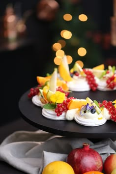 a black plate topped with cupcakes covered in fruit