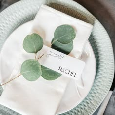 a place setting with napkins and eucalyptus leaves