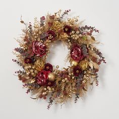 a christmas wreath with red flowers and gold ornaments on it's side, against a white background