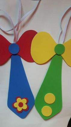 three colorful wooden tags with bows and flowers on them, hanging from a white ribbon